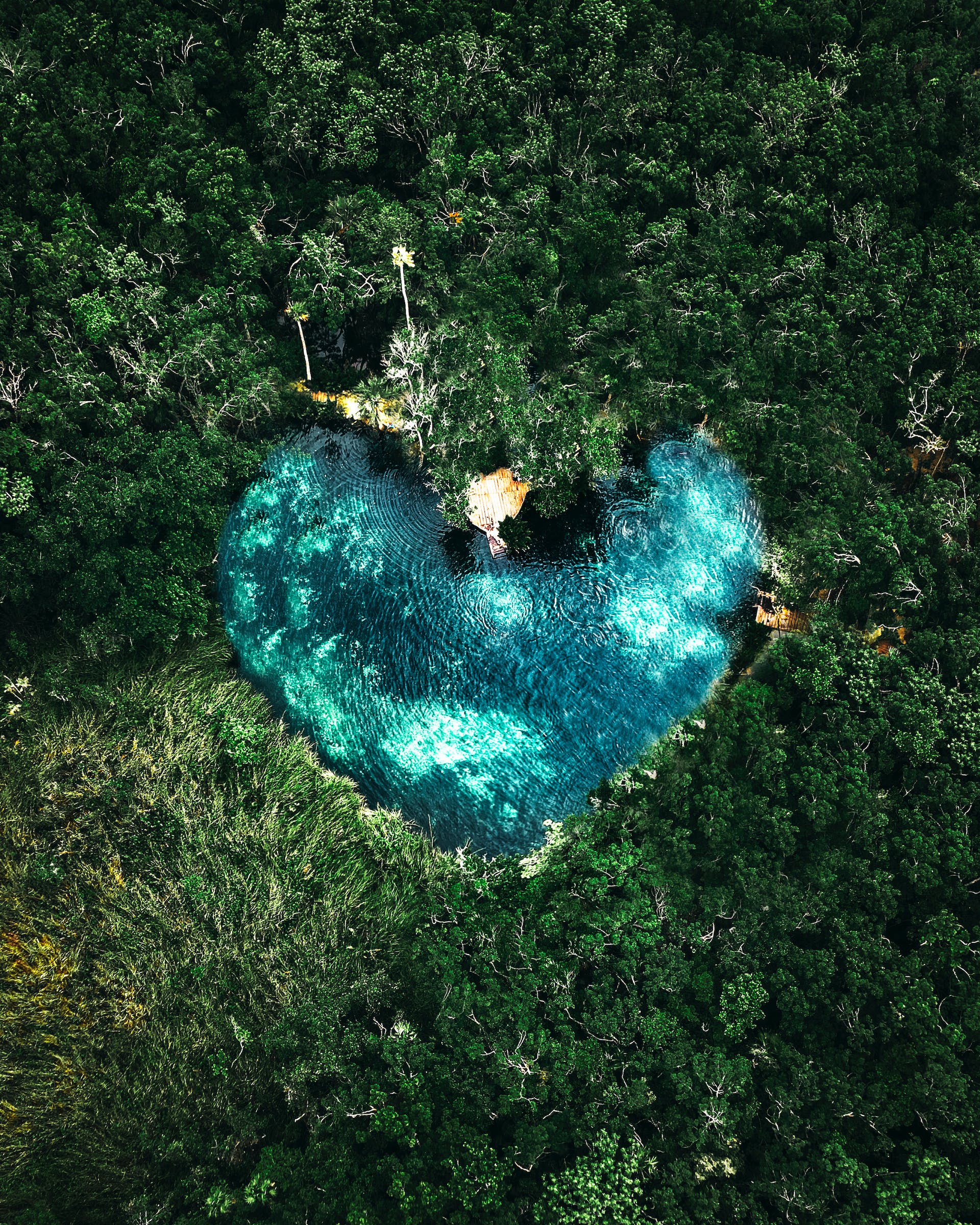 Aerial view of a heart-shaped cenote surrounded by Tulum's lush jungle